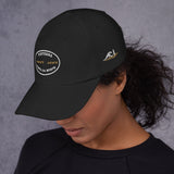 Gorra Fisterra CF Negro - mujer con gorra vista lateral, bordado frontal y lateral visible. Mockup oficial Printful, Costa da Morte.