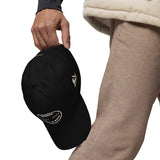 Gorra Fisterra CF Negro - detalle premium de gorra en mano con bordado lateral. Mockup oficial Printful, Costa da Morte.