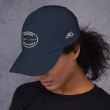 Gorra Fisterra CF Azul marino - mujer con gorra vista lateral, bordado frontal y lateral visible. Mockup oficial Printful, Costa da Morte.