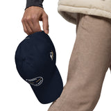 Gorra Fisterra CF Azul marino - detalle premium de gorra en mano con bordado lateral. Mockup oficial Printful, Costa da Morte.