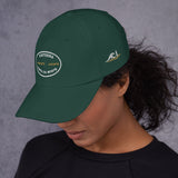 Gorra Fisterra CF Verde abeto - mujer con gorra vista lateral, bordado frontal y lateral visible. Mockup oficial Printful, Costa da Morte.