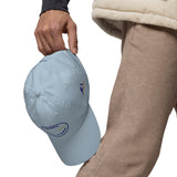 Gorra Fisterra CF Azul cielo - detalle premium de gorra en mano con bordado lateral. Mockup oficial Printful, Costa da Morte.
